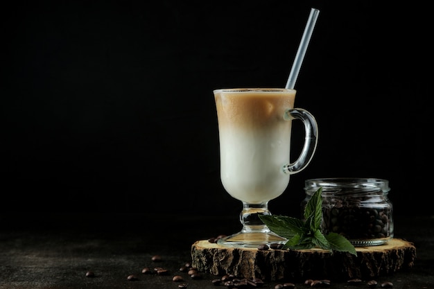 Ice latte or Iced coffee with milk and ice cubes in a glass beaker against a dark background. refreshing drink. summer drink.