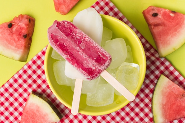 Ice lolly in bowl near napkin and slices of fresh fruit