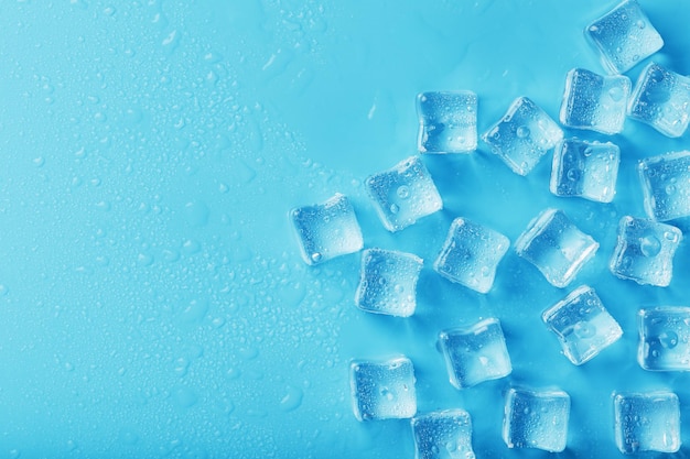 Ice made of cubes lined up with drops on a blue