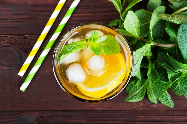 Ice tea with lemon and mint on a wooden background