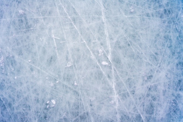 Ice with marks from skating and hockey, blue texture of rink surface with scratches