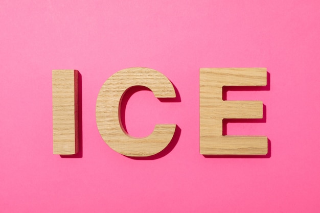 Ice word made from wooden letters on pink background