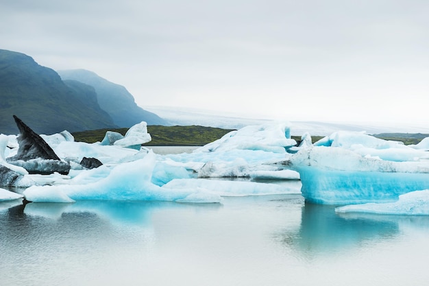 Icebergs in the glacial lake with mountain views. Vatnajokull glacier, Fjallsarlon lagoon, south Iceland