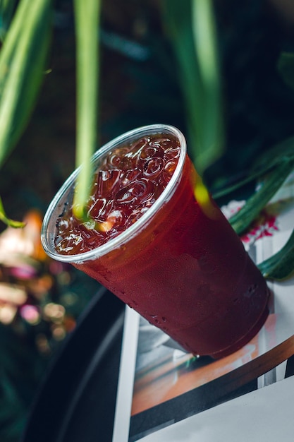 Iced Americano coffee or black coffee in plastic glass on a wooden table in the garden