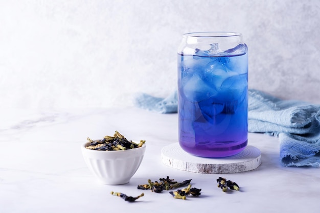 Iced butterfly pea flower tea and dry clitoria ternatea petals on white background blue anchan