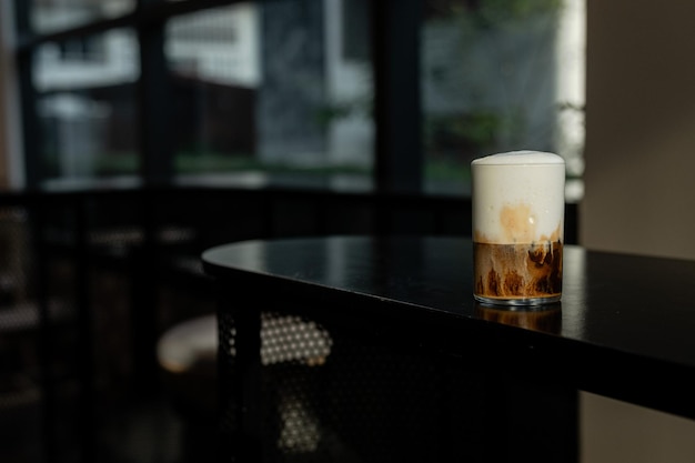 Iced cappuccino on a black table with cream being poured into it, showcasing its texture.