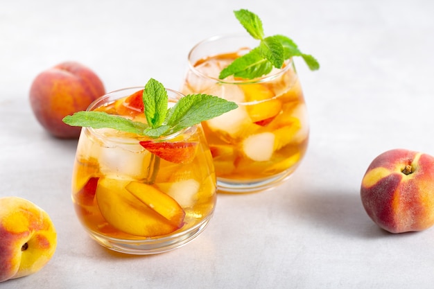 iced carbonated tea with peaches and mint in a glasses