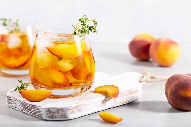 iced carbonated tea with peaches and  thyme  in a glass