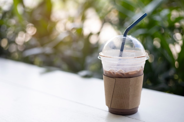 Iced cocoa in plastic cup on the table green background