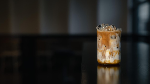 Iced coffee latte on a table with cream being poured into it, showcasing its texture.