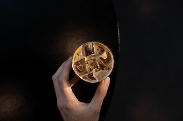 Iced coffee latte on a table with cream being poured into it, showcasing its texture.