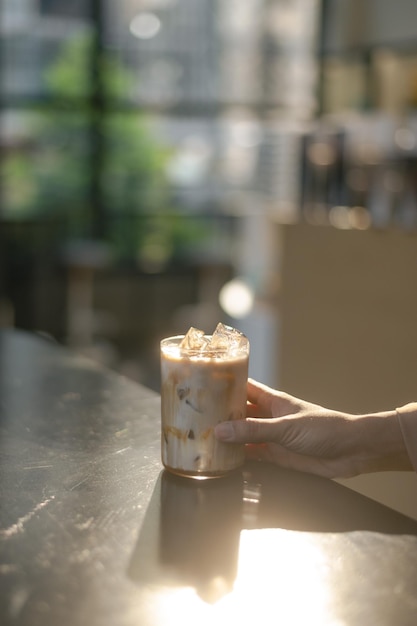 Iced coffee latte on a table with cream being poured into it, showcasing its texture.