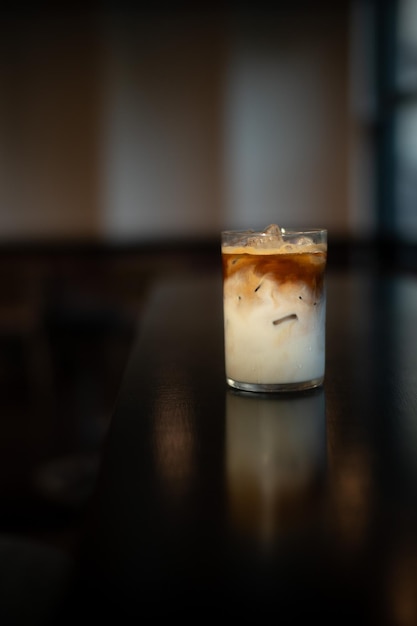 Iced coffee latte on a table with cream being poured into it, showcasing its texture.