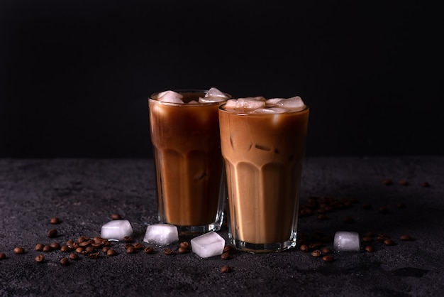 Iced coffee in a tall glass with cream poured over. Wood background. Low key.