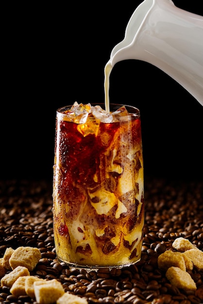 Iced coffee tasty ice coffee with milk cold drink in glass with ice on dark coffee background