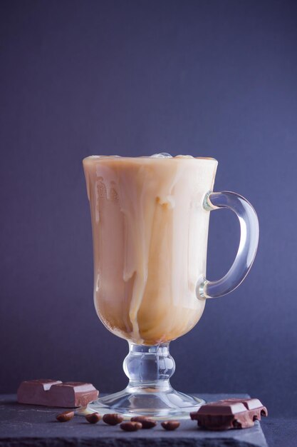 Iced coffee with milk on dark background Latte and black chocolate on slate board Milk drink