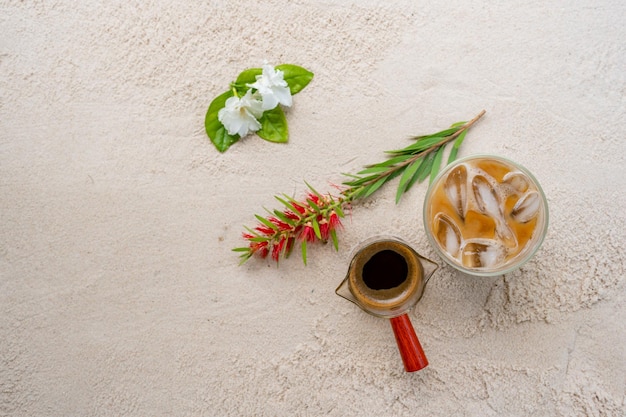 Iced coffee with milk on sand beach background.