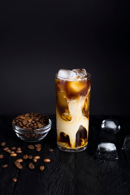 Iced coffee with milk in a tall glass on the dark background Closeup Location vertical