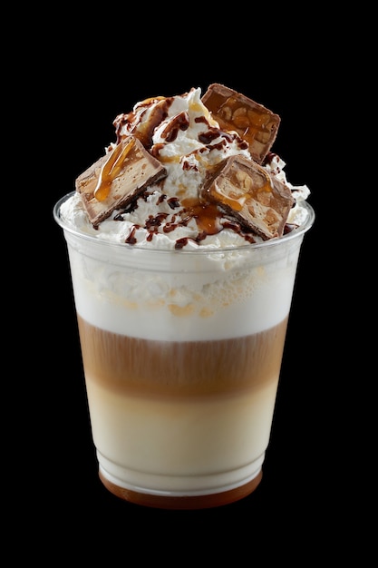 iced coffee with whipped cream, ice cream and topping in a plastic glass on black background