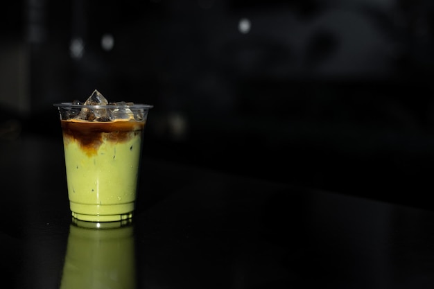 iced green tea with milk in plastic cup put on black table