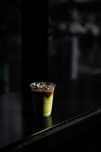 iced green tea with milk in plastic cup put on black table