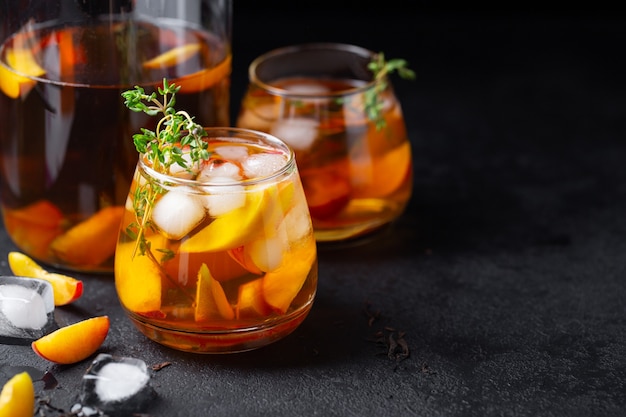 iced homemade black tea with peaches and thyme in a glass o