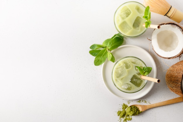 Iced latte green matcha tea with coconut on white background. View from above.