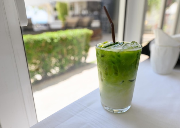 Iced matcha green tea with milk with straw in glass