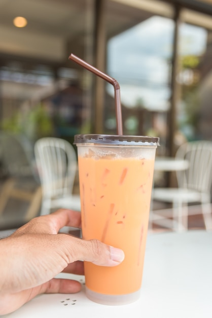 Iced Milk Tea with straw in plastic cup on a  table in summer