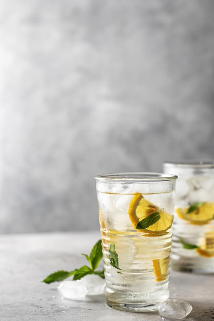 Iced refreshing detox water with lemon mint in glasses Homemade lemonade or cocktail Space for text