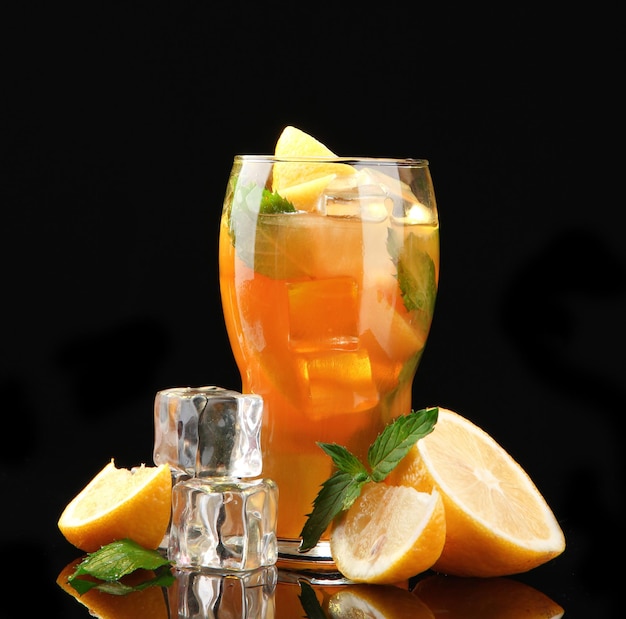 Iced tea with lemon and mint on black background