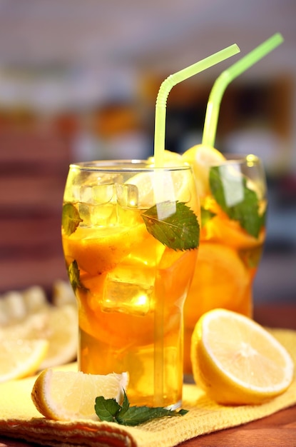 Iced tea with lemon and mint on wooden table outdoors