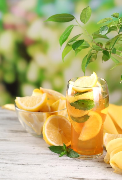 Iced tea with lemon and mint on wooden table outdoors