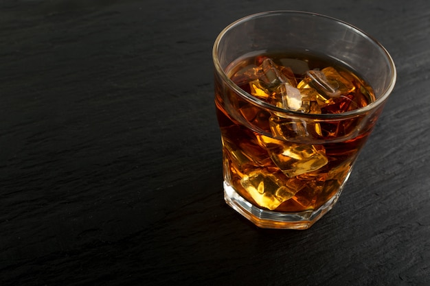 Iced Whiskey Glass on Natural Black Stone Background