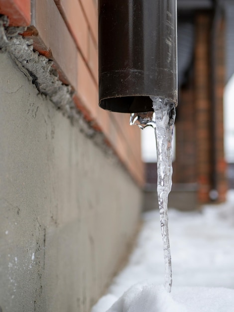 Icicle sticking out of the drainpipe After a heavy snowstorm the city is covered with snow and ice