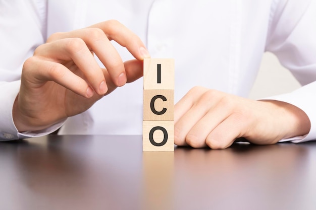 Ico Initial coin offering text on cube blocks in businessman hands man in white shirt