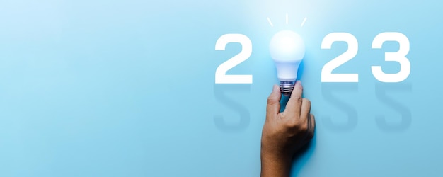 Idea and creative in 2023 lighting bulb with new year number on blue background