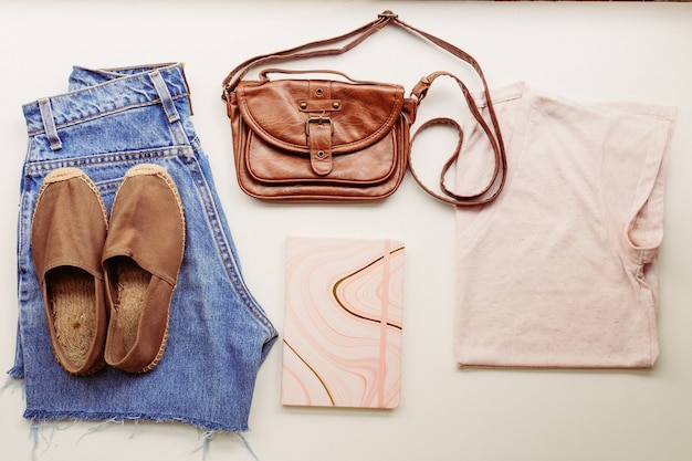 Ideal clothes for summer outfits: a shirt, jeans, a bag, shoes. View from above.