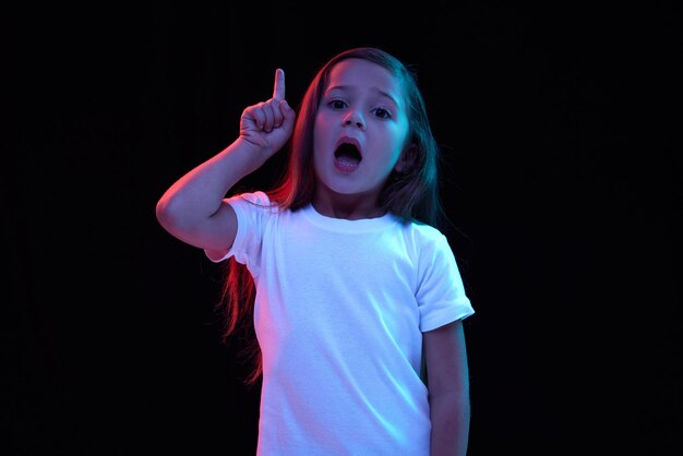 Ideas charming little girl kid in white tshirt expressing emotions isolated over dark background