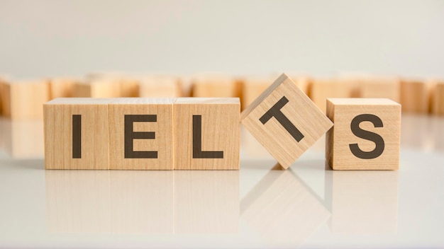 ielts - word of wooden blocks with letters on a gray background. reflection of the caption on the mirrored surface of the table. selective focus.