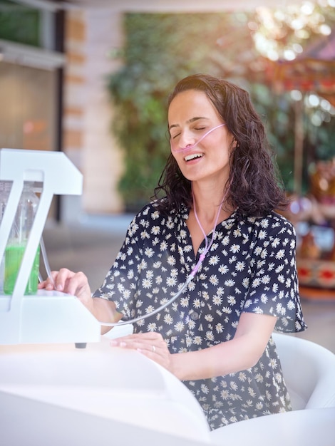 Ill female sitting at table and singing song with closed eyes while treating with nasal breathing aid