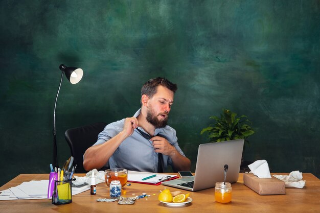 Photo ill young man with fever and cold looks suffering at home