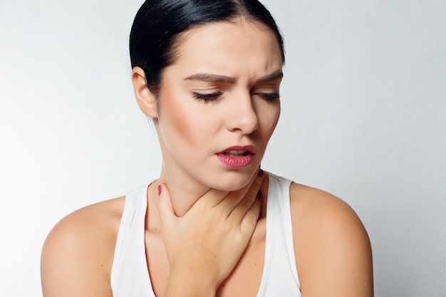 Illness, Health Care, people, Medicine concept - Throat Pain. Closeup Of Sick Woman With Sore Throat Feeling Bad, Suffering From Painful Swallowing. Beautiful Girl Touching Neck With Hand