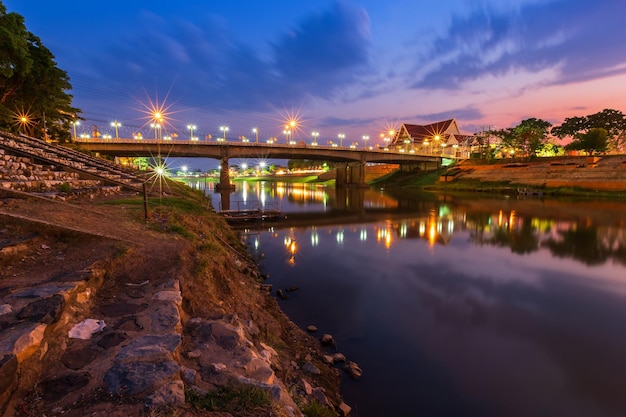 Photo illuminated bridge over river against sky at night