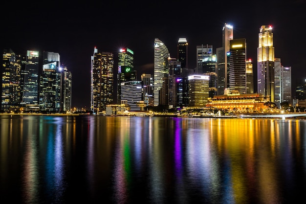 Illuminated buildings by river against sky at night