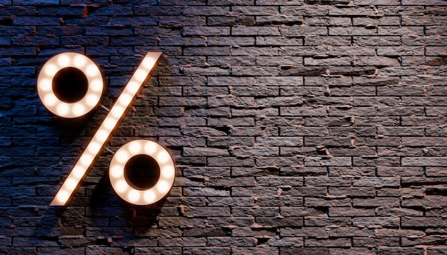 Illuminated percent sign hanging on brick wall