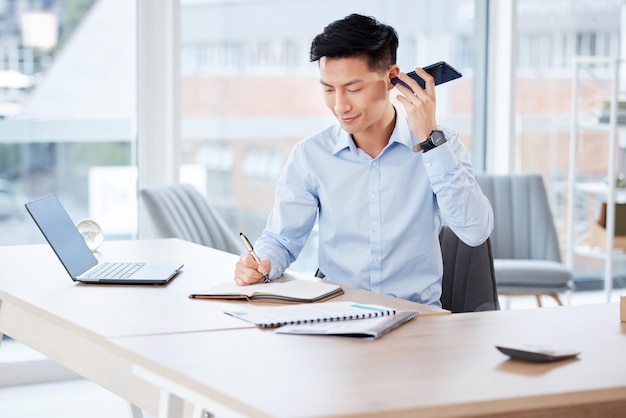 Im always getting great ideas. Shot of a young businessman writing in a notebook while on a call in a modern office at work.