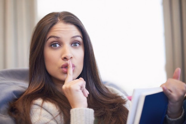 Im trying to read here Portrait of a young woman shushing the camera while reading a book