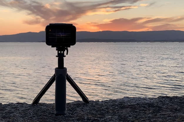 Image of action camera on a tripod photographing the sunset over the ocean close-up