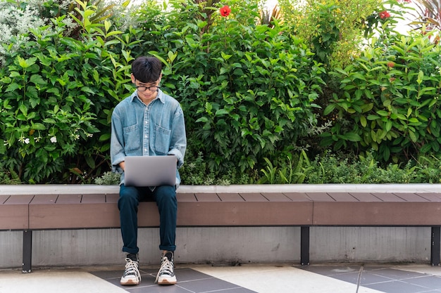 Image of asian boy sitting and using computer in school campus